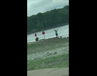 Green shirt guy poses arms up lake 