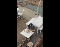 Man getting a shower from a storm drain while eating