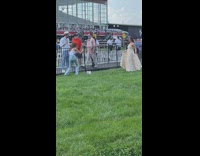Woman in a dress poses on the side of the horse track
