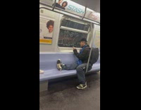 Guy riding subway writes on window glass 