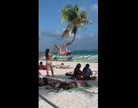 Woman in bikini hangs on the tilted tree