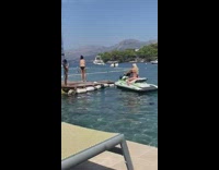 Woman in bikini poses in the jet ski while kid takes picture