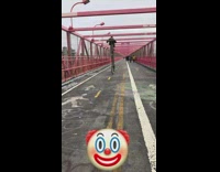 Man rides a giant bicycle with one giant wheel down red bridge 