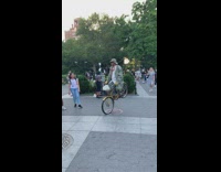 Guy balancing perfectly still on one front wheel on bicycle at park 
