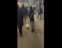 Lady and white duck walk down sidewalk together 