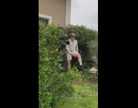 Guy stands next to tall bush 