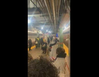 Woman twerks upside down with legs on wall to banjo music in subway station