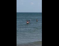 Guy plays clarinet instrument in ocean water