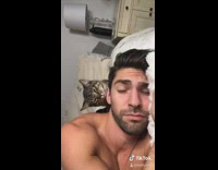 Shirtless guy in bed grey brown cat