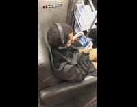 Guy sits on sofa couch seat and watches movie on phone on subway train
