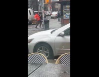 Man orange jacket dances at the sidewalk