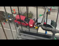 Person in small red car successfully gets out of tight spot