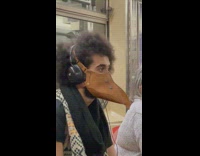 Guy sitting on train wears beak face mask 