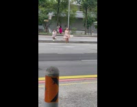 Woman in beige dress hops and spins in the middle of the street
