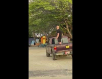 Guy holds selfie stick while on pickup truck 
