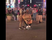 Barber gives guy a haircut in salon chair in the middle of street intersection, black car honks