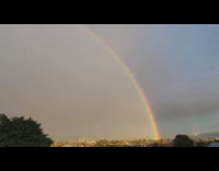 Double rainbow arc over trees balcony overcast
