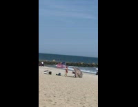 Shirtless guy sets up American flag on beach 