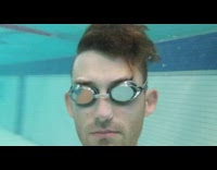 Man shirtless swims underwater with camera phone