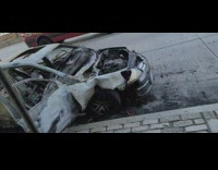 Destroyed car next to sidewalk 