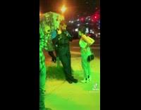 Girl falls on sidewalk as other girl hits on cop