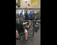Guy spins barbell weight around over his head at the gym