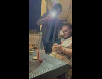 Two men lights and takes picture of bottle of wine