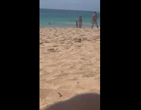 Guy films girl dancing on beach sand 