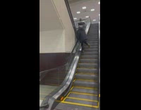 Man in black winter jacket walks up the down escalator in the mall