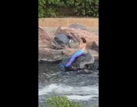 Blue mermaid tail girl sits rock river 