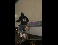 Guy riding bicycle does wheelie by truck 