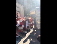 Group of Santa Claus wait outside Louis Vuitton store with news anchors 