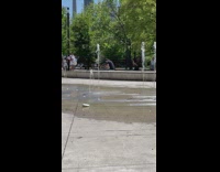 Woman in white outfit with a bag walks by the fountain