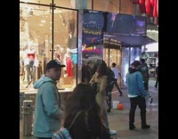 Guy dances looks at reflection clothing store 