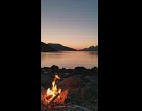 Sun sets behind mountains over lake bonfire 