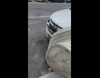 White car hits the big flower pot on the side of the street