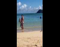 Man flexes back muscle at the beach