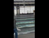 Woman poses in front of the tripod on the moving walkway