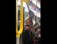 Woman with pointy hair and chain clothes rides the subway