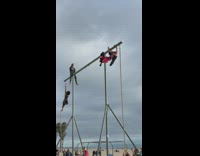 Woman in red robe pole dance and hang at the beach