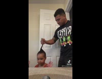 Daughter spins around while dad holds hair to create bun hairstyle