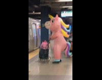 Person in unicorn costume waits for train 
