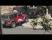 Guy dances for video in front of red jeep 