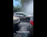 Cars passing by a broken fire hydrant spraying water all over cars