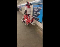 Woman wears red white black balloon animal dress in subway station