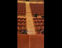 Woman black dress ballet pose theater chairs