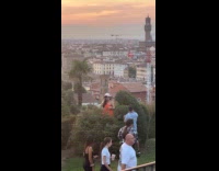 Woman orange top poses behind the bush