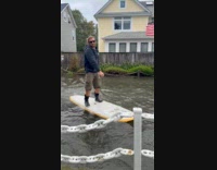 Guy rides paddle board on flooded street