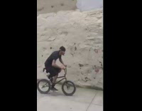Guy rides up ramp and jumps over rail, bike wheel gets stuck on rail and throws guy on sidewalk