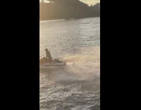 Joker wearing purple suit rides red jet ski 